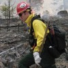 Photos by Amy Veneziano<br>A firefighter continues to set fire while a ponderosa pine burns up in a crown fire behind him. Crown fires can send flames as much as 300 feet into the air.