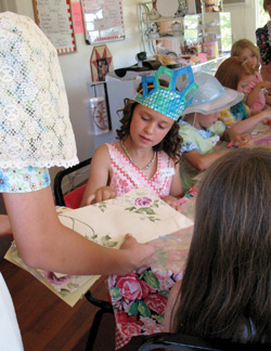 Photo by Amy Veneziano	With her crown complete, one little girl picks out the perfect paper for a hand fan from helper Mishara, 13 years old. 