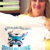 Michelle Smith, President of the May Festival Committee holds up this year's festival T-shirt, with the "Let the Good Times Roll" design by Princess Cheyanne Sharpe. Photo by Gary DeVon