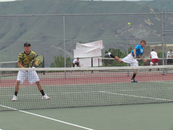 Senior Brett Hendrick serves the ball to his Liberty Bell opponents during the final round of the District 6 tennis tournament in East Wenatchee at Eastmont High School on Saturday, May 21 while his doubles partner, senior Lee Leavell, remains ready close