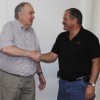 Jim Prince and Jack Hughes shaking hands on Hughes and his wife Mary taking over the Prince's Department Store and Ace Hardware and Prince's Warehouse business.