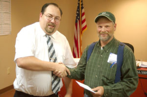 Tonasket Mayor Patrick Plumb (left) presents Bill Burman of the city engineering firm of Varela and Associates with a gift certificate as thanks for his work on the Bonaparte Creek/Mill Drive water and sewer project. Brent Baker/staff photo.