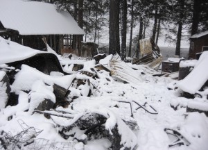 Snow covers the remains of the burnt-out cabin.