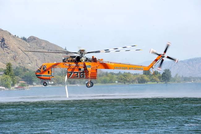 A heavy lift, air crane helicopter sucks water from Osoyoos Lake near Oroville's Veterans Memorial Park last Monday morning. The water was later dropped on the Wildhorse Fire burning on Mt. Hull Near Summit Lake.