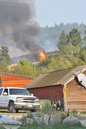 Fires broke out in several locations last Thursday, Aug. 13. It can be seen making it way toward a Chesaw-Oroville Road residence, but was stopped short by retardant and water bombing planes and helicopters. Photo by Gary DeVon