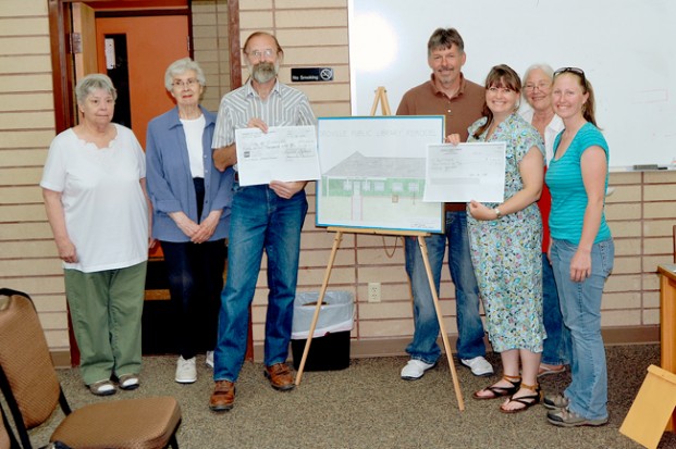 The Oroville Library Board and Friends of the Library presented checks to the City of Oroville for the public library remodel - one for $57,000 and the other for $7000. Pictured with Oroville Mayor Pro Tem Jon  Neal are (l-r) Sue Geisler, Marilyn McCullough, David Wolosik, Neal, LaVonne Hammelman, Salley Bull and Stephanie Hart. Gary DeVon/staff photo