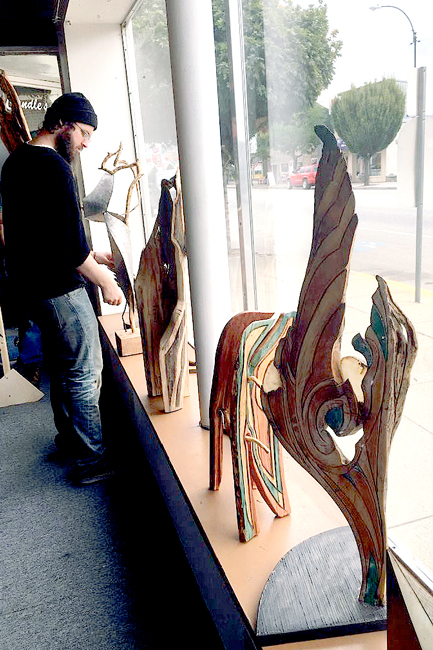 Daniel Klayton, a founding member of the 49º North Artists, helps to set up Hulphers sculptures in the window,  just one  of  several featuring local artists. Submitted photo