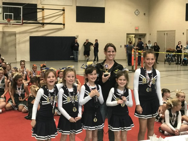 Submitted photo  The Oroville Honey Bees Cheer Squad (L-R) Sandra Minigell, Isabella Elias-Rothell, Mylee Taber, Alexis Lindsay and Renee Wold with coach Lisa Lindsay, show off their trophy and medals after competing in the league competition in Spokane. Their first place finish earned them the right to compete in the Regional event in California later this month.