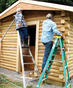 Photo by Amy Veneziano        Three members of the Comancheros put the finishing touches on the new beer garden building at the Tonasket Rodeo Grounds. The building is made from the same lo