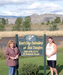 Photo by Gary DeVon Jennifer Finsen (left) and her sister Carrie Buckmiller near the sign for the new Riverâ€™s Edge Embroidery store. Finsen, who used to work at Ethyls on Main Street in Oroville, is opening the busi