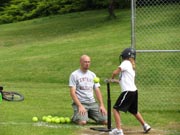 Photo by Emily HansonTim Cork, the head softball coach for Tonasket High School, teaches one the girls on the last day of the sports camp how to hit a softball off the tee properly.