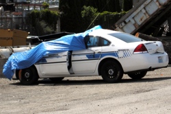 Officer Patterson's Patrol Car in the Oroville equipment yard behind the Depot Museum. Covered with a blue tarp, much of the wreckage is hidden from view, but emergency personal at the scene described the damage caused by the collision with a cow on Hwy.