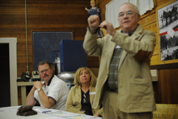 Okanogan County PUD Commissioner Ernie Bolz (standing) answers a question from the audience at a special meeting of the PUD Commissioners held at the Oroville Depot. Bolz and his fellow commissioners, David Womach and Trish Butler, as well as District Man