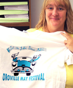Michelle Smith, President of the May Festival Committee holds up this year's festival T-shirt, with the "Let the Good Times Roll" design by Princess Cheyanne Sharpe. Photo by Gary DeVon