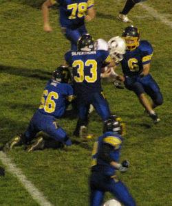 Tonasket senior linebacker Dustin Silverthorn (33) wraps up an Okanogan Bulldog with the help of sophomore linebacker Dalton Wahl (66) as senior linebacker Keegan McCormick (6) heads in to help. Also on the way to help with the tackle are senior defensive