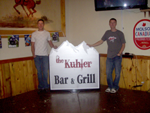 Zach and Josh Kuhlmann pose by the new Kuhler Bar and Grill sign which is now up on it's post in front of their business at the home of the former Tonasket Saloon. Photo by Charlene Helm