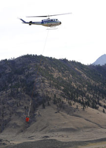 A helicopter, one of four dropping water on the fire on the hillside near the Nighthawk-Chopaka border crossing last Monday afternoon. Photo by Gary DeVon