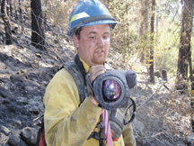 Tim Hoffman, an infrared field observer for the Washington Interagency Incident Management Team, shows the palm IR camera he used on the Buffalo Lake Road Fire.  The camera is protected from dust and impact by a padded cover. The camera weighs about four