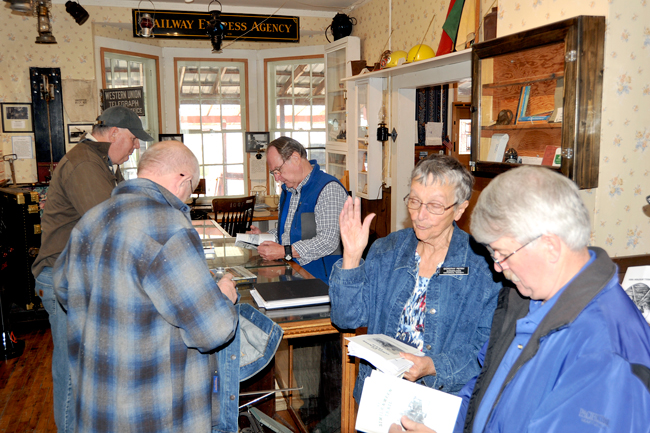 Borderlands Historical Society president Dorthy Petry offers GNRHS members copies of their booklet "The Similkameen Trail," a collection of articles, pictures and history along the trail which follows the path of the Great Northern which linked the line with points north in Canada. Left, Tedi Lynn Fletcher serves up stew and shares a laugh with a a member of the Great Northern Railway Historical Society. Gary A. DeVon/staff photo September 23, 2016