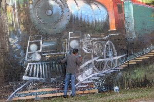 Gary DeVon/staff photo Local artist Rahim Abari works on a large mural on the back of the Camaray Motel that depicts Oroville’s early railroad history.