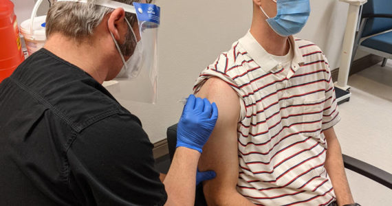 Submitted photo
The day after the <em>G-T</em> interviewed North Valley Hospital District Administrator John McReynolds the district received it’s first shipment of vaccine. Pictured here is Jeff Massart, a Physical Therapist employed by NVH. As a health care worker he received the Pfizer vaccine to prevent the spread of COVID-19 on Wednesday morning, Dec. 16. The shot is being administered by Michael Oberg, RN.