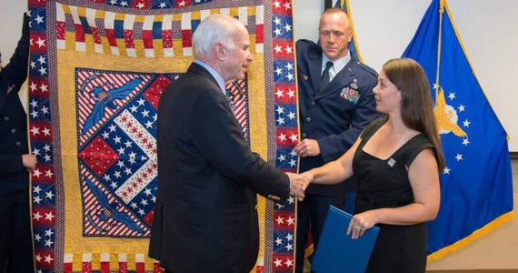 The late U.S. Senator John McCain, USN Retired, being awarded his Quilt of Valor by Michelle Nelson, QOVF Board of Directors. An as yet unamed Quilts of Valor group is forming in the Tonasket area. QOV photo
