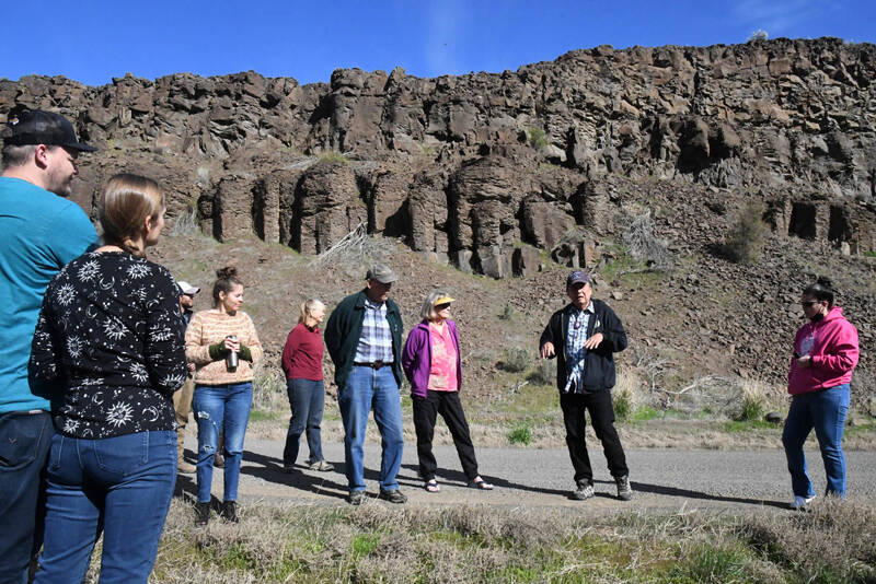 In a photo taken Saturday, April 22, 2023, tribal elder and storyteller Randy Lewis stands in front of the “Singing Rocks” of Moses Coulee, explaining how they absorbed the voices of his people and how those voices can still be heard – if the conditions are right. (Dominick Bonny for Crosscut)