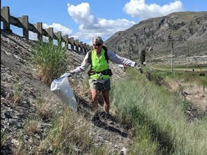 A volunteer helps pick up litter on Hwy. 97 near Crumbacher in a previous years Adopt-A-Highway clean up.