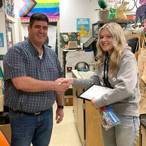 Okanogan Transit Authority General Manager Brent Timm congratualtes Avery Brown for her winning artwork at Okanogan High School. Submitted photo