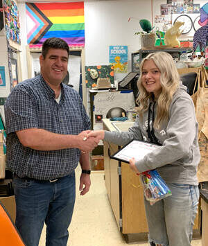 Okanogan Transit Authority General Manager Brent Timm congratualtes Avery Brown for her winning artwork at Okanogan High School. Submitted photo