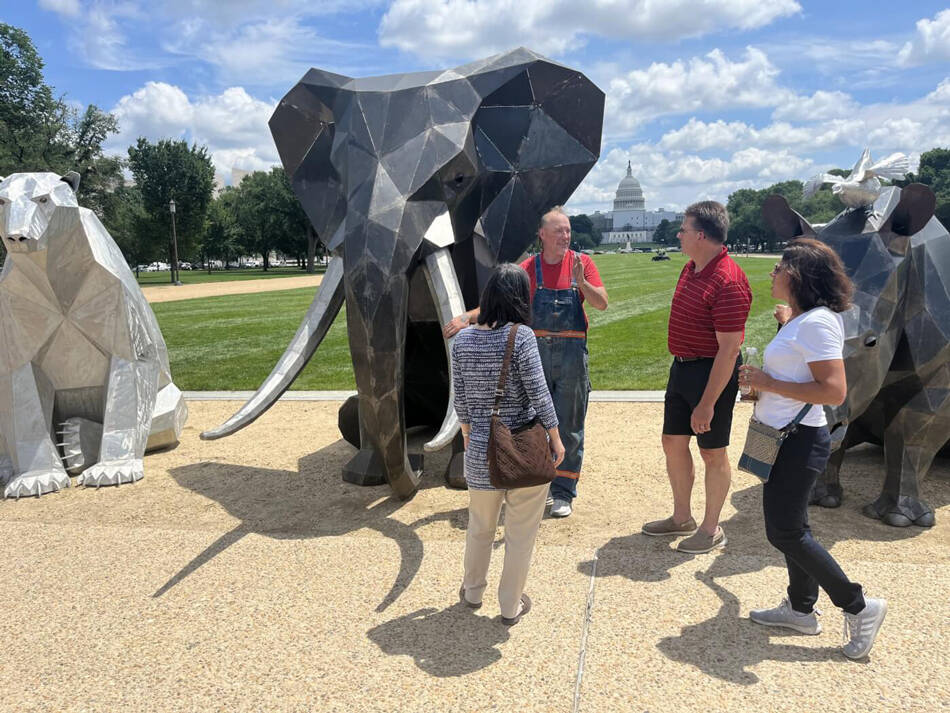 Artist Quill Hyde speaks with some of the visitors to the National Mall about their artwork.