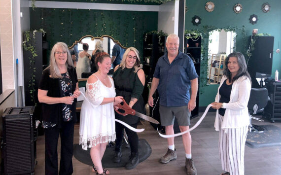 Eva Brenon and Tasha Gordon use the big scissors to cut the ribbon at their salon in a ceremony held by the Oroville Chamber of Commerce. Also pictured are Oroville Chamber Board Member Peggy Shaw and Chamber President Rocky DeVon and Chamber Secretary Laura Curdie. <em>Gary DeVon/staff photo</em>