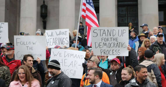 Washingtonians from all over the state gathered on the north steps at the capitol in Olympia, for a rally planned only a week in advance. Protesters displayed signs that read “We want hearings,” and “Follow the constitution.” Photo by Aspen Anderson