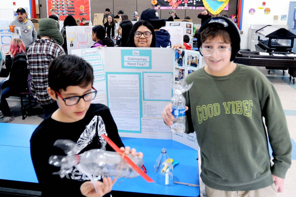 Alredo Alejandre winds up a twin rubber band powered model sub made from a plastic bottle. He was paired up with Choice High School student brandi Rodriguez pon a project titled do submarines need fins. Aslo pictured is fifth-grader Rowan Jones. <em>Gary DeVon/staff photos </em>