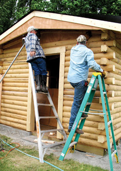 Photo by Amy Veneziano        Three members of the Comancheros put the finishing touches on the new beer garden building at the Tonasket Rodeo Grounds. The building is made from the same lo