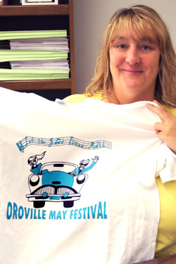 Michelle Smith, President of the May Festival Committee holds up this year's festival T-shirt, with the "Let the Good Times Roll" design by Princess Cheyanne Sharpe. Photo by Gary DeVon