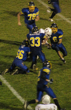 Tonasket senior linebacker Dustin Silverthorn (33) wraps up an Okanogan Bulldog with the help of sophomore linebacker Dalton Wahl (66) as senior linebacker Keegan McCormick (6) heads in to help. Also on the way to help with the tackle are senior defensive