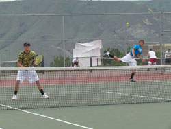 Senior Brett Hendrick serves the ball to his Liberty Bell opponents during the final round of the District 6 tennis tournament in East Wenatchee at Eastmont High School on Saturday, May 21 while his doubles partner, senior Lee Leavell, remains ready close