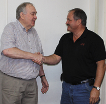 Jim Prince and Jack Hughes shaking hands on Hughes and his wife Mary taking over the Prince's Department Store and Ace Hardware and Prince's Warehouse business.