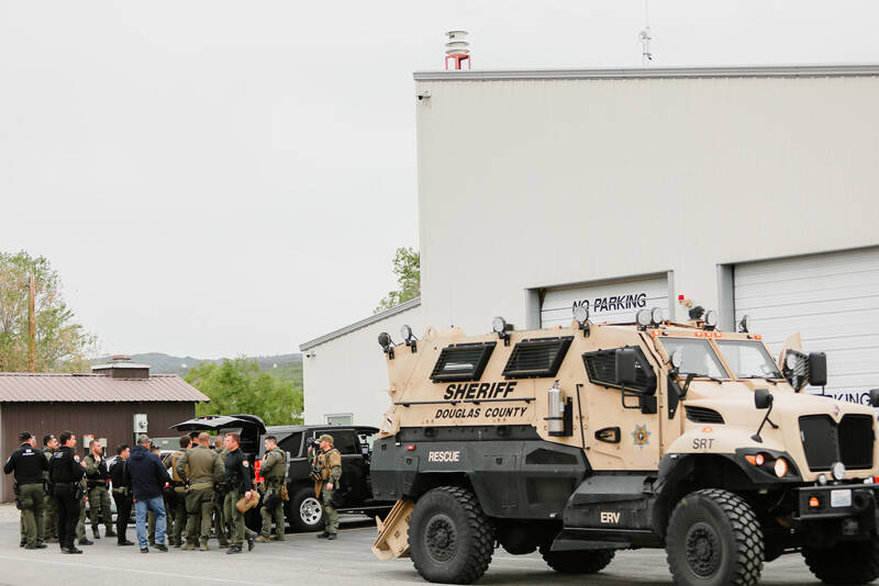 Okanogan County Sheriff s Deputies, the North Central Washington Special Response Team and the East Cascade SWAT Team gather in Tonasket to discuss an attempt to serve a search warrant on a Loomis man Wednesday. The attempt was made after the man, who is prohibited from owning firearms, is alleged to have fired during a dispute with neighbors in the Toats Coulee area.	<em>Laura Knowlton/staff photos</em>