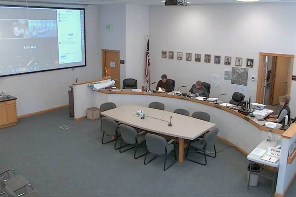 The Okanogan County Commissioners met Tuesday, March 28 and opened the bids for the contact to publish the countys legal advertising at 10:30 a.m. Seated are, l-r, Commissioner Jon Neal, Commissioner Andy Hover and Clerk of the Board Lanie Johns. Chris Branch, chairman of the Board of Commissioners, who met via Zoom, can be seen on the screen on the wall to the left. The commissioners awarded the bid to be shared by the Okanogan Valley Gazette-Tribune and the Methow Valley News. <sub><em>Zoom Screen Capture </em></sub>