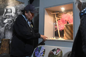 Lewis points to a display case featuring cxelusa bulbs, a hand-woven basket, and a traditional puca made of wood and a piece of antler at the Colville Tribal Museum in Grand Coulee, Wash. on Saturday, April 22, 2023. (Dominick Bonny for Crosscut)