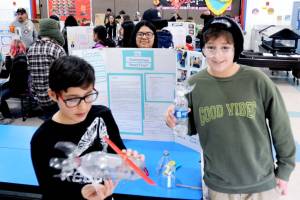 Alredo Alejandre winds up a twin rubber band powered model sub made from a plastic bottle. He was paired up with Choice High School student brandi Rodriguez pon a project titled do submarines need fins. Aslo pictured is fifth-grader Rowan Jones. <em>Gary DeVon/staff photos </em>